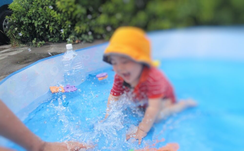 幼児が熱中症対策の帽子をかぶって水遊びをしている様子