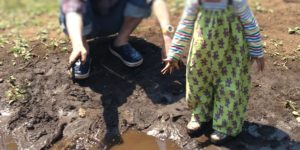 幼児がプレーパークでエプロンをかけて泥遊びをしているところ